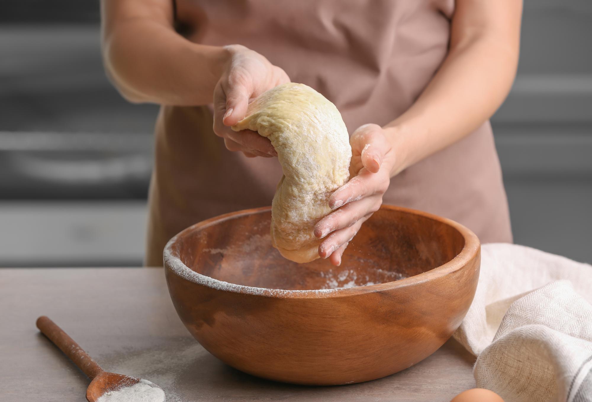 hands kneading dough in bowl