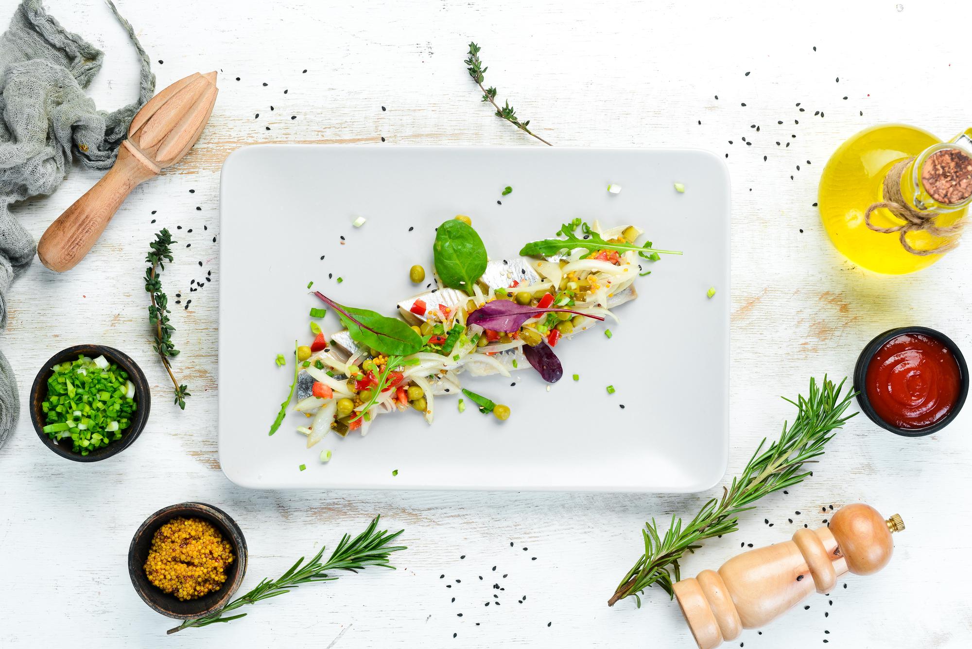 chef plating a composed dish with herbs